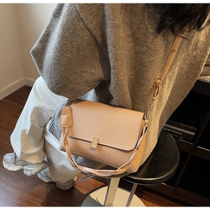 Detail of pink PU crossbody bag featuring a gold metal clasp and woven handle strap