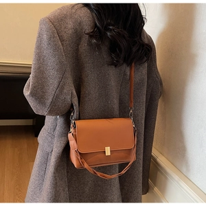 Brown retro shoulder bag with gold clasp shown on model wearing dark brown blazer