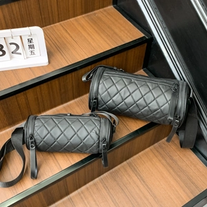 Quilted cylinder crossbody bags in two sizes on wooden stairs with matte black finish