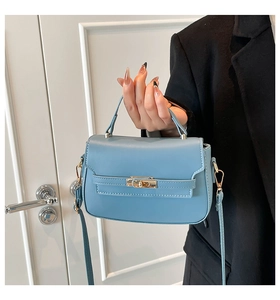 Close-up of matte fog blue leather handbag featuring a golden turn-lock and strap