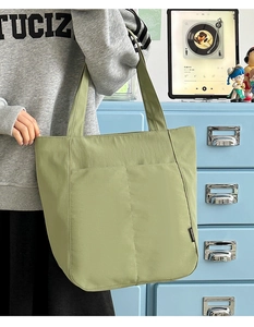 Große grasgrüne Tragetasche mit Vordertaschen und modischem Seitenlabel im Detail