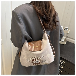 Detail of canvas shoulder bag with brown leather flap and baseball graphic print