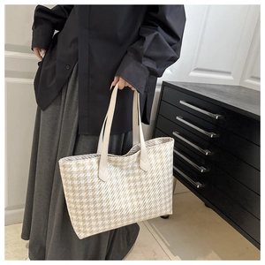 Detail of beige woven tote bag with plaid pattern and cream leather handles for women