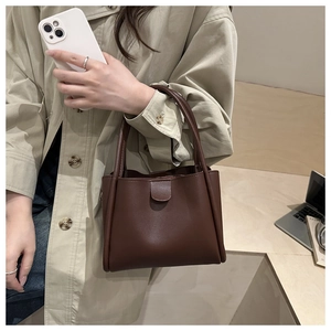 Deep brown leather tote bag held by a model in a beige coat for a stylish office commute