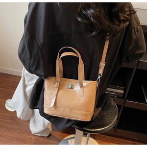 Détail du sac seau en cuir avec fermoir rotatif argenté et bandoulière réglable
