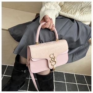 Close-up of pink crossbody bag with snakeskin texture and gold S-shaped buckle held by model