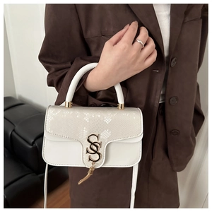 Detail of white faux leather bag with snake pattern texture and gold S hardware