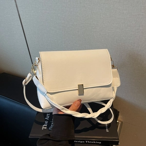 White vintage shoulder bag with gold clasp and woven strap shown in handheld lifestyle view