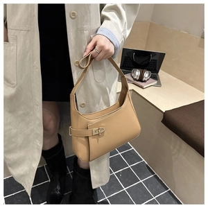 Chic camel hobo shoulder bag with gold buckle detail worn by model in a modern office set