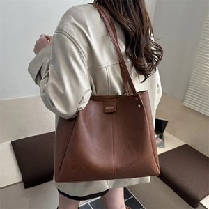 Large brown leather tote bag for women featuring a minimalist trapezoid design and shoulder strap