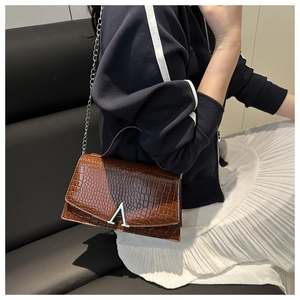 Detailed close-up of brown croc-effect handbag with silver A-shaped metal buckle