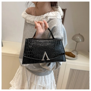 Model holding a black crocodile pattern handbag with a silver V-shaped buckle