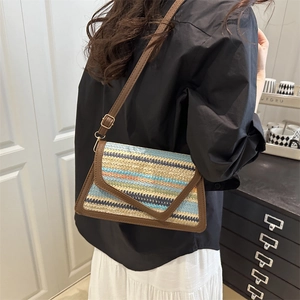 Chic multi-color striped woven crossbody bag with brown leather strap worn by a model