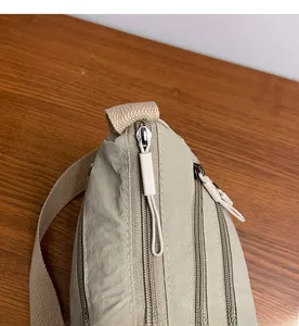 Dettaglio delle doppie cerniere e della trama in nylon della borsa a tracolla kaki