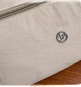 Dettaglio ravvicinato della borsa in nylon beige con texture e logo in metallo