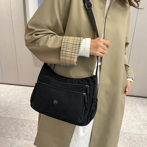 Dettaglio borsa a tracolla in nylon nero con vari scomparti a zip e logo metallico JP tondo