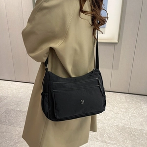Dettaglio borsa a tracolla in nylon nero con tasche multiple e tracolla regolabile
