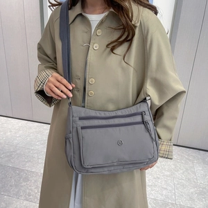 Dettaglio della borsa a tracolla in nylon grigio con scomparti multipli e zip rifinite