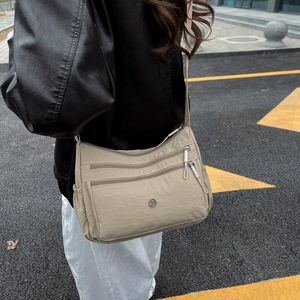 Dettaglio della borsa a tracolla in nylon kaki con tasche multiple e tracolla regolabile