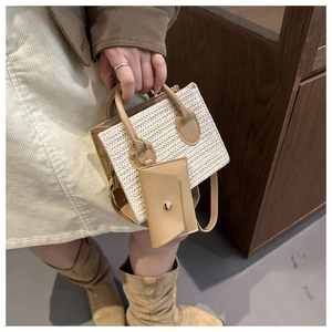 Detail view of woven straw tote bag with brown faux leather trim and mini charm