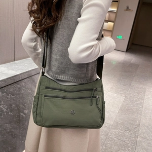 Borsa a tracolla in nylon verde militare con design multitasca indossata per scala e misura