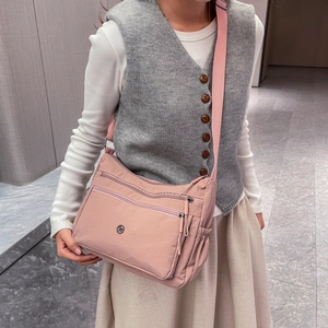 Dettaglio borsa a tracolla in nylon rosa chiaro con tasche a zip indossata dal modello