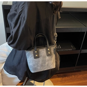 Detail view of grey frosted leather tote bag with black handle and gold rivet accents
