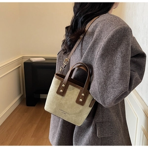 Detail of vintage suede bucket bag with leather handles and removable strap shown on a model