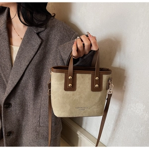 Close-up of khaki canvas and brown leather mini bucket bag with fashion logo and gold hardware