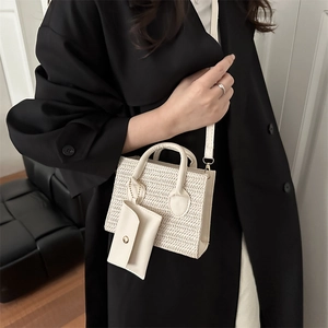 Woven crossbody handbag in beige with matching small coin pouch on a black coat
