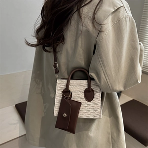 White and beige woven straw mini handbag with brown handles and a long shoulder strap