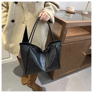 Close-up of black crocodile pattern leather tote bag shown in a stylish lifestyle setting