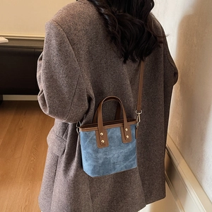 Blue denim mini bucket bag with brown leather trim shown cross-body on a model