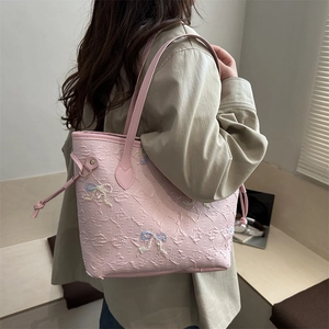 Pink faux leather tote bag with F-letter embossing and beaded bow in a lifestyle setting