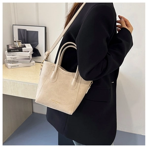 Detail of cream leather handbag showing fine texture and adjustable strap in office setting