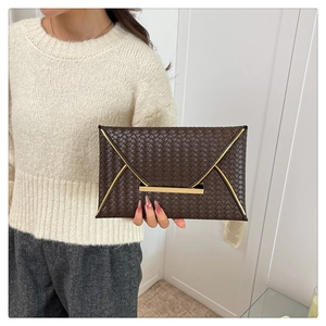 Détail de la pochette tressée marron foncé avec garniture métallique dorée en forme de V