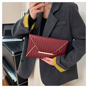 Détail de la pochette enveloppe en cuir tressé rouge avec bordure dorée élégante