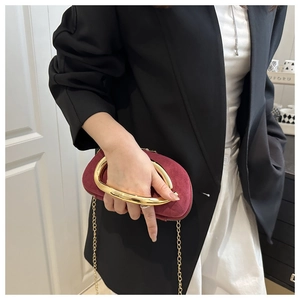 Detail of burgundy suede mini evening bag with chunky gold metal handle and chain strap