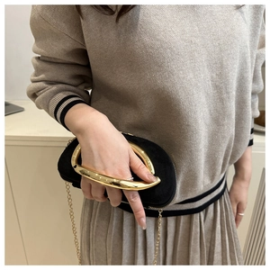 Detail of black suede round bag with large gold ring handle and metal chain strap