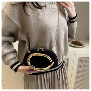 Detail of a black oval evening bag featuring a gold metal ring handle and chain strap