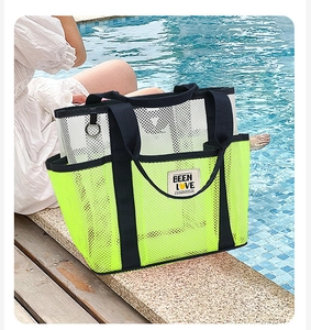 Detail of neon yellow mesh beach tote with outer pocket and webbed handles by pool