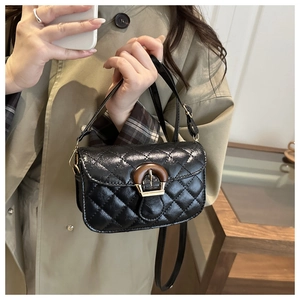 Detail of a black quilted leather crossbody bag with a vintage circular wooden buckle closure