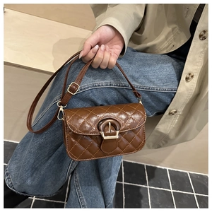 Detailed view of brown quilted oil wax leather texture and gold buckle on shoulder bag