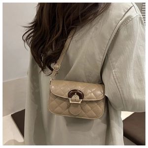 Detail of khaki quilted shoulder bag featuring vintage wood and metal clasp closure