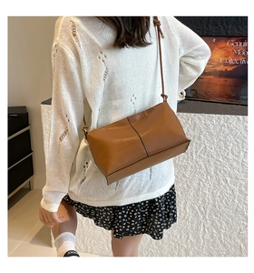 Close-up of minimalist brown leather crossbody bag with adjustable strap and vertical stitching