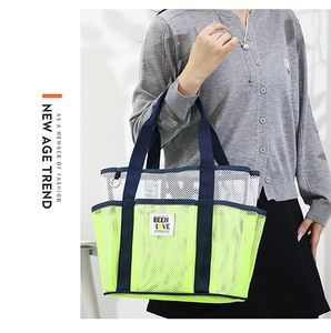 Detailed close-up of large mesh tote bag featuring green contrast base and slogan patch