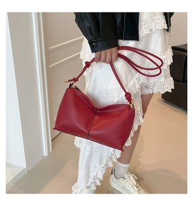 Detail of red leather shoulder bag with knot strap and gold metal buckle adjustment