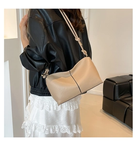 Detailed view of beige leather underarm bag featuring a unique knotted shoulder strap