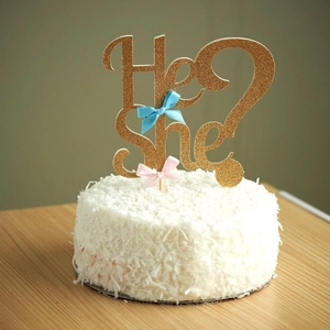 Close-up of glittery He or She cake topper with blue and pink bows for gender reveal