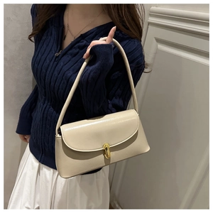 Close-up of creamy faux leather underarm bag with elegant gold buckle and fine texture